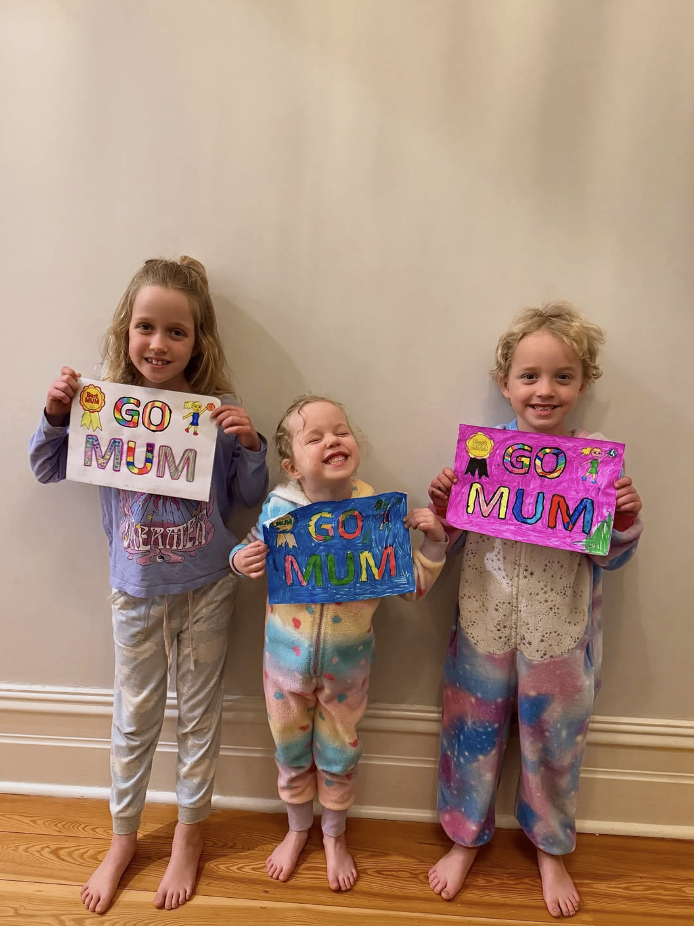 Three children proudly holding colourful handmade signs during a creative activity in Adelaide