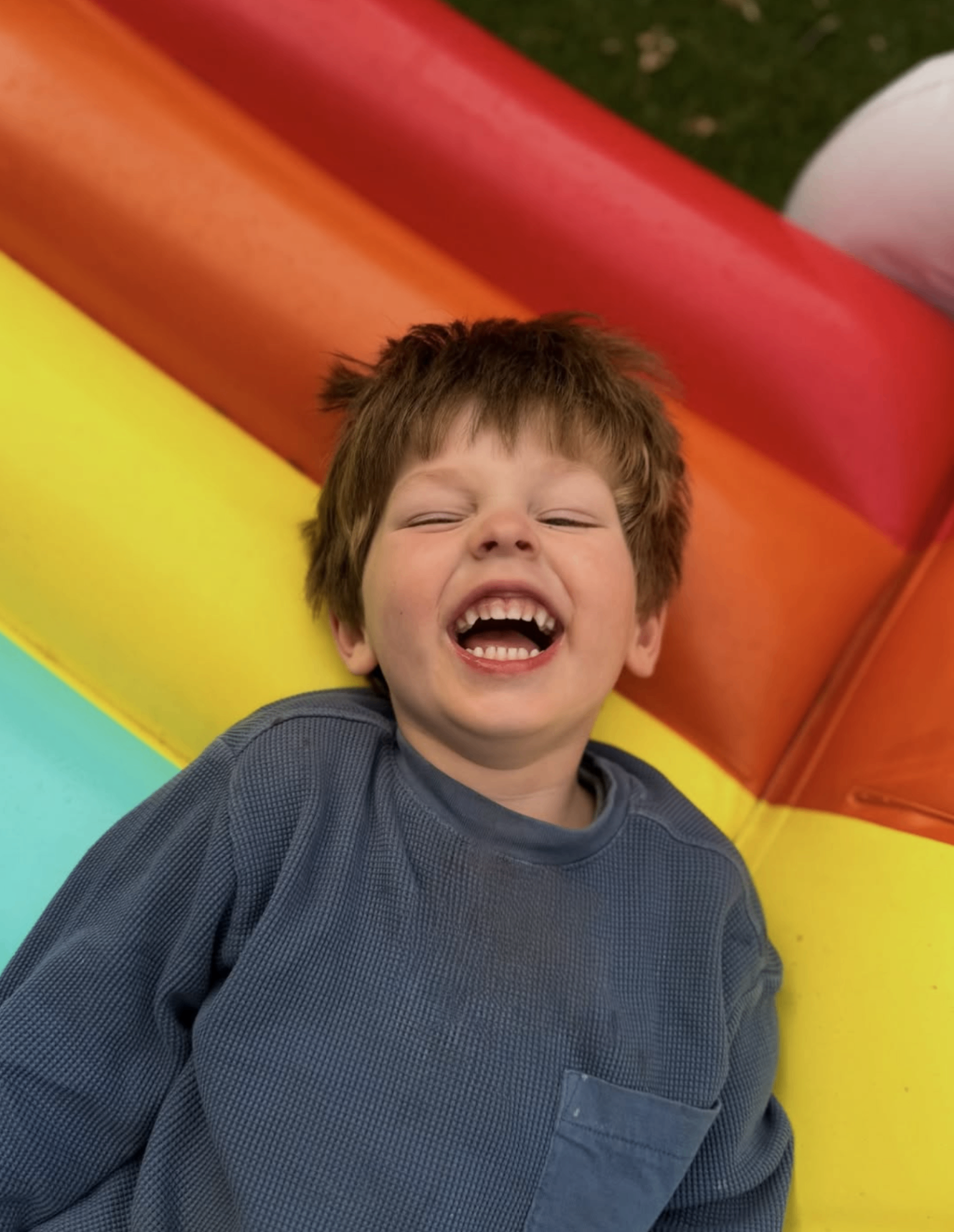 Young child laughing at the bottom of a colourful slide during an Adelaide play outing